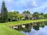 Waterfront property featuring manicured lawns, mature specimen trees, and established landscaping