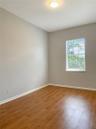 Room featuring wood-finish flooring, neutral wall paint, and a singular window with horizontal blinds, illuminated by a flush-mount ceiling fixture