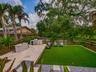 Backyard with outdoor kitchen, turf, and mature tree canopy