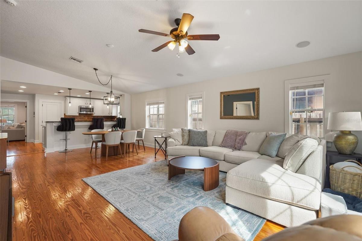 Living room with vaulted ceiling open to the dining area and kitchen