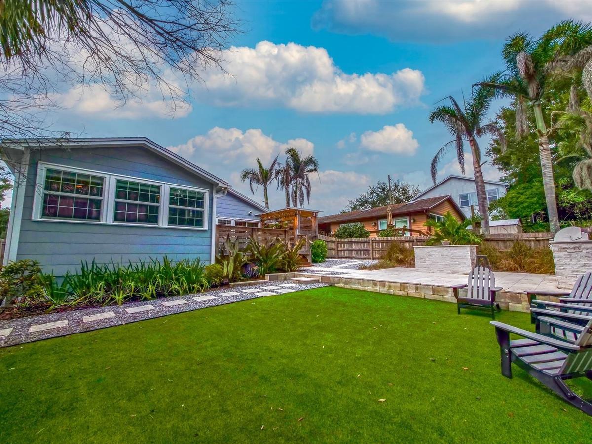 Backyard turf with rear exterior, pergola deck, and outdoor kitchen