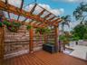 Rear deck with pergola, string lights, and view of the outdoor kitchen