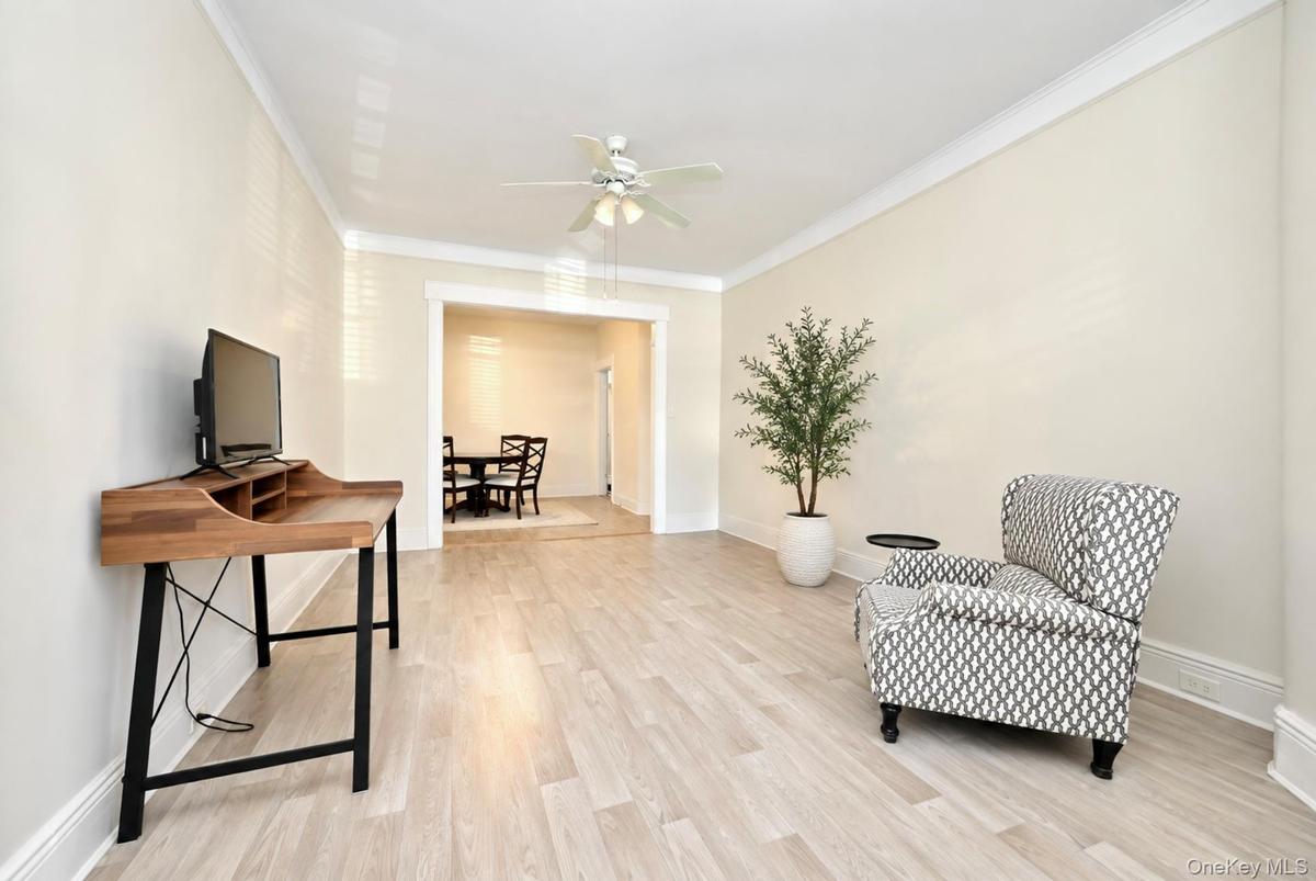 1st. Floor: Light-filled room featuring wood-finish flooring, crown molding, and a central ceiling fan with integrated lighting