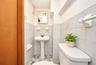 White pedestal sink with a dual-handle faucet, integrated wall-mounted medicine cabinet, square ceramic wall tiling, and mosaic-patterned flooring