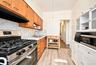 2nd. Floor: Kitchen featuring natural wood-finish cabinetry, stone-patterned countertops, a stainless steel gas range, wood-finish flooring, and white