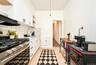 1st Floor: Kitchen featuring white cabinetry with matte black hardware, stainless steel gas range, stone-tiled backsplash, and wood-finish flooring