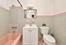 2nd. Floor: Bathroom featuring pastel tile wainscoting with accent trim, a pink porcelain soaking tub, white vanity cabinet with a integrated sink, wa