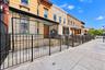 Brick townhouse exterior featuring a warm-toned masonry facade, decorative wrought iron security fencing, a multi-pane wood entry door, and ornate cor