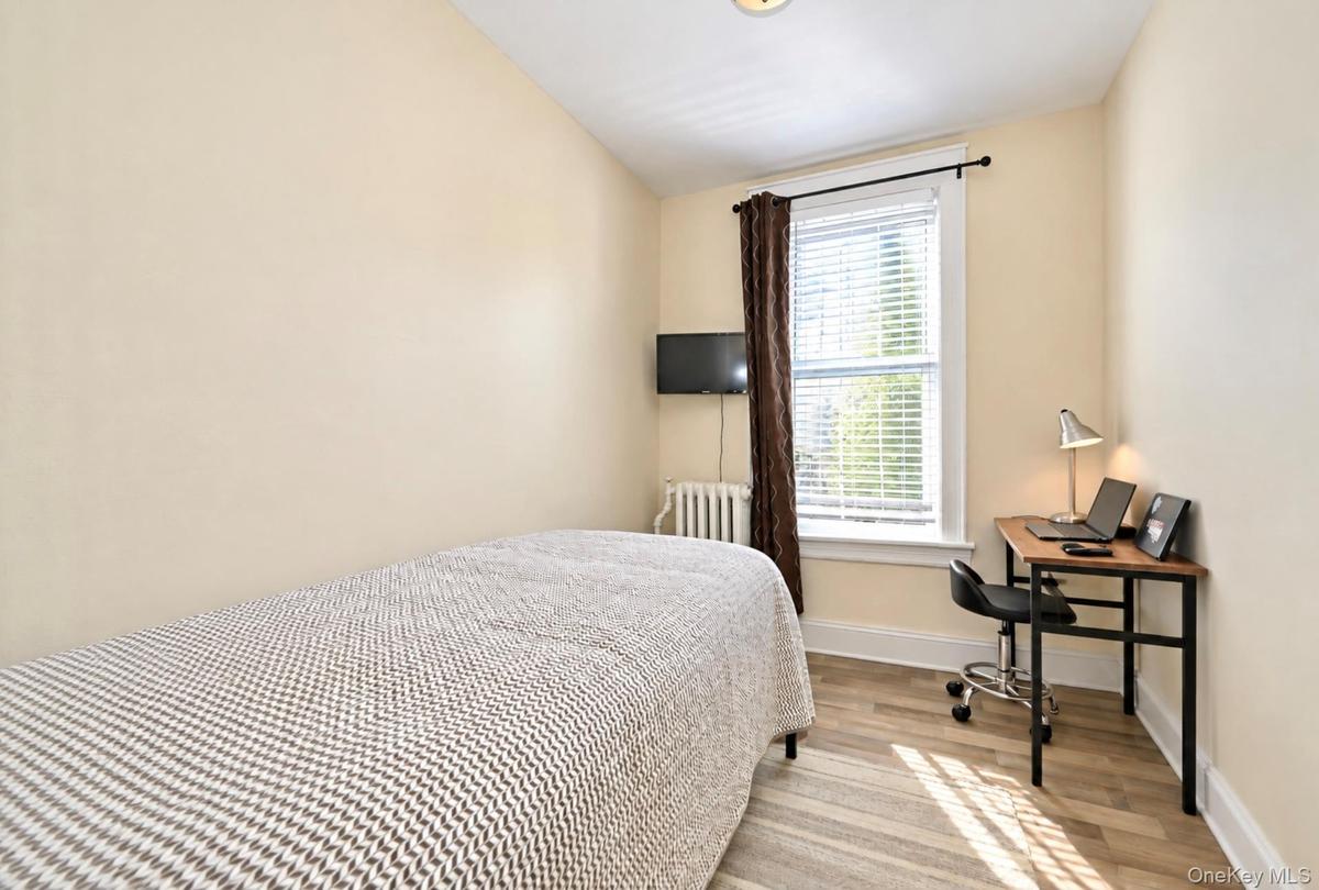 2nd. Floor: Neutral-toned walls, wood-finish flooring, a single-hung window with casing, and a classic metal radiator