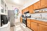 2nd. Floor: Kitchen featuring wood cabinetry, stone-finish countertops, herringbone-pattern tile backsplash, stainless steel appliances, and wood-fini