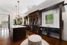 Dark wood-finish flooring with a central storage island, built-in glass-front cabinetry, and custom window shutters