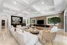 Coffered ceiling with recessed lighting, integrated wet bar, large windows with white shutters, wall-mounted media console, and stone tile flooring