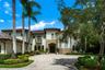 Mediterranean Revival architectural style with a tile roof, stone accents, and a paved circular driveway