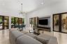 High ceilings with crown molding, stone-finish flooring, multiple sets of glass French doors, and an open-concept living and dining area