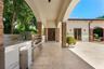 Outdoor kitchen featuring integrated stainless steel appliances, white stone-finish countertops, and a built-in grill