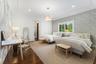 Wood-finish flooring, recessed lighting, crown molding, a window with plantation shutters, and a drum pendant light fixture