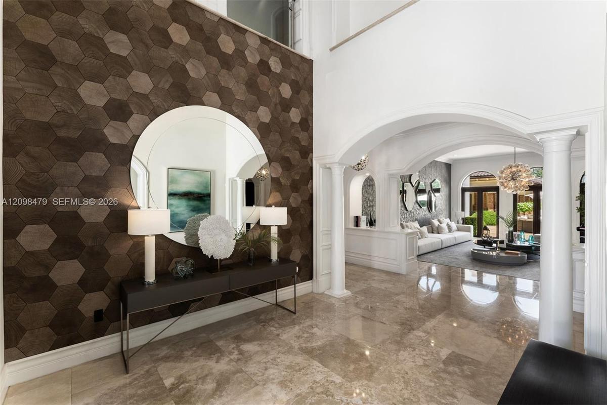 Hexagonal accent wall, polished stone flooring, arched doorways, interior columns, and a double-height ceiling