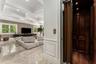 Polished stone flooring, coffered ceiling, multiple windows with plantation shutters, wood-paneled interior elevator, and recessed lighting