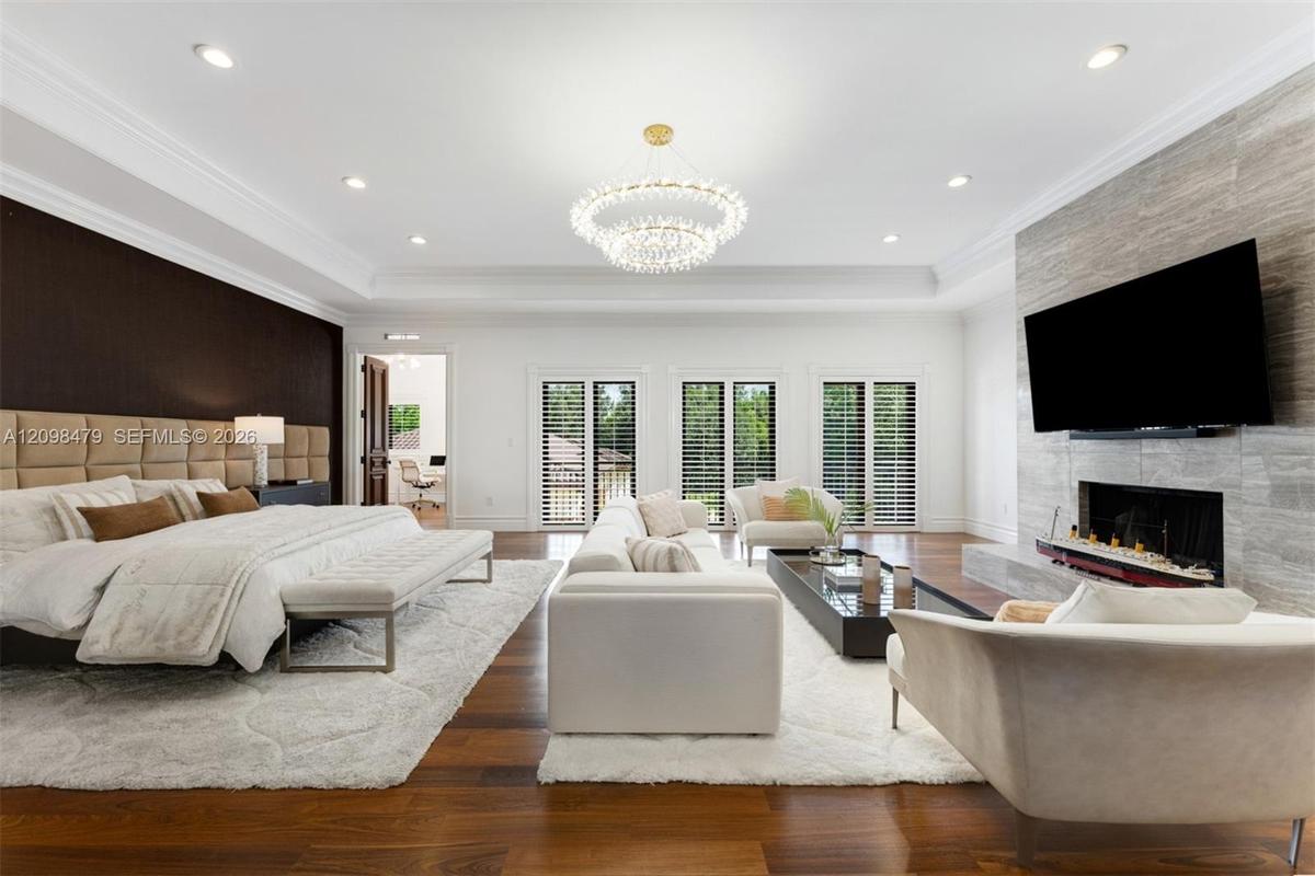 Hardwood flooring, recessed lighting, tray ceiling, chandelier, and a stone-clad fireplace