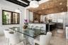 Recessed lighting, exposed brick ceiling, wood-frame window, paneled cabinetry, and stainless steel appliances