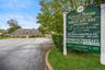 Professional building featuring brick exterior construction, multi-gabled roofline, asphalt parking area, and dedicated roadside signage
