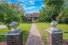 Cape Cod exterior featuring shingle siding, a brick walkway, and twin brick entrance pillars topped with spherical finials
