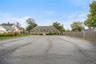 Brick exterior featuring a multi-gabled roofline, arched window detailing, and an extensive asphalt parking area