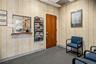 Interior space featuring neutral wallpaper, a solid wood-finish door, a pass-through window with a wood-finish ledge, and carpeted flooring