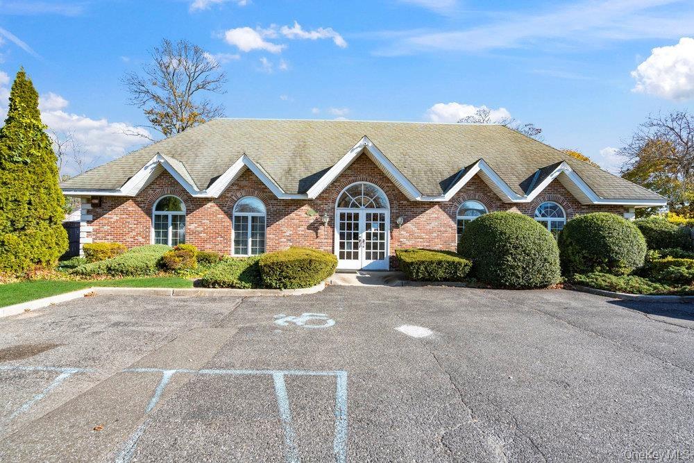 Brick facade featuring multiple gables, arched windows, and a central arched double-door entry