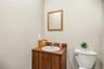 Vanity featuring a wood-finish cabinet, integrated countertop, and inset circular sink, complemented by a rectangular wall-mounted mirror