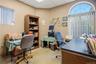 Office space featuring a built-in wooden shelving unit, an arched window with fixed fanlight, and vertical blinds