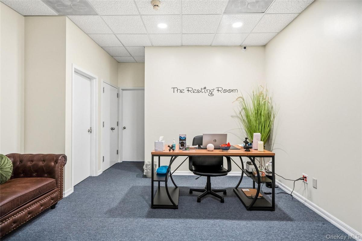 Neutral-toned interior space featuring a suspended drop ceiling, recessed lighting, wall-to-wall carpeting, and multiple solid-core entry doors