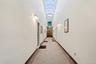 Hallway featuring an arched vaulted skylight, patterned tile flooring, and wall-mounted sconce lighting
