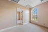 Arched window with decorative muntins, carpeted flooring, drop ceiling with recessed lighting, and a single-light glass-panel interior door