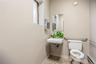 Wall-mounted sink with a rectangular basin, metallic wall-mounted paper dispenser, framed mirror, and chrome grab bars