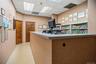 Reception area featuring a built-in transaction counter with a durable surface, integrated metal shelving, wood-veneer doors, drop ceiling with recess