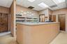 Reception area featuring an L-shaped service counter, suspended ceiling tiles with integrated lighting, two solid wood doors, and built-in shelving un