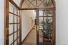 Double entry doors featuring a wooden frame, glass panes, and brass hardware, complemented by a semi-circular transom window and mosaic tile flooring