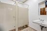 Restroom featuring floor-mounted partition stalls, a wall-mounted sink with chrome-finish hardware, and a framed wall mirror