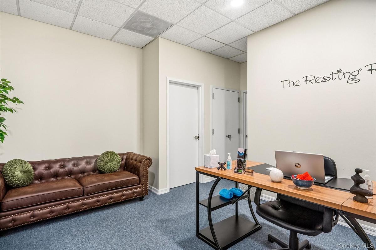 Interior space featuring neutral-toned walls, textured ceiling tiles, and blue carpeting