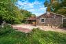 Cedar shake siding, red paver patio, stone retaining wall, and covered porch area
