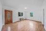 Solid wood front door with decorative glass inlay, laminate flooring, white wainscoting, and multi-pane windows