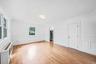 Bright freshly painted interior featuring laminated flooring, extensive wainscoting, crown molding, and arched doorway