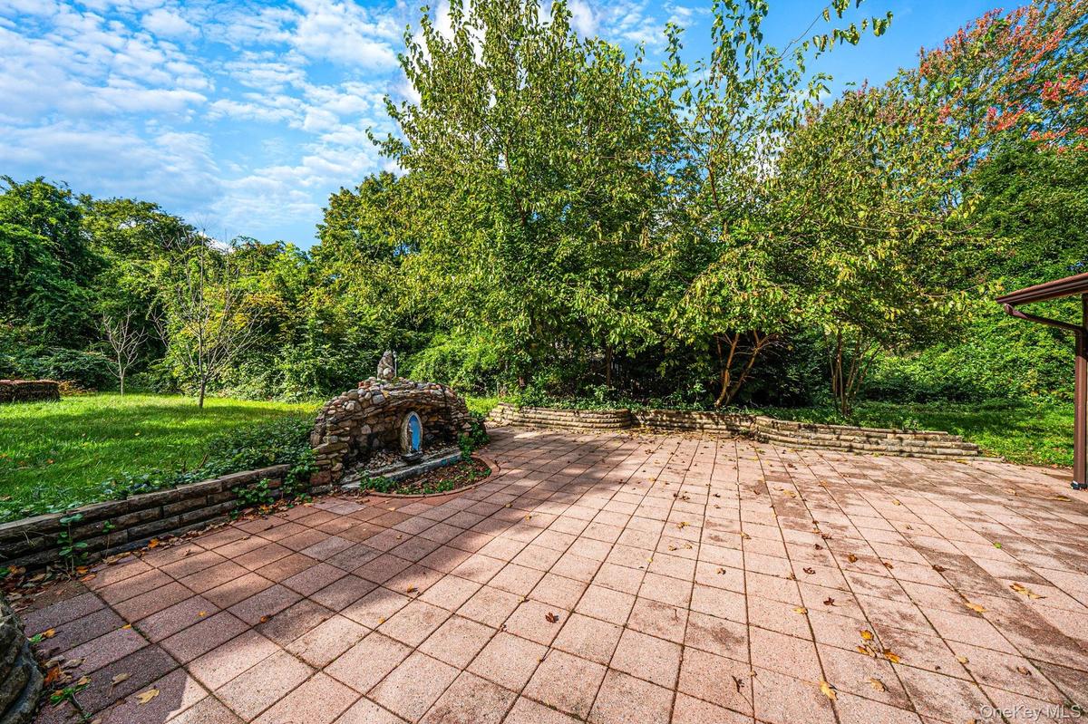 Paver patio featuring stacked stone retaining walls, integrated stone masonry structure, and expansive wooded lot