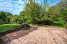 Paver patio featuring stacked stone retaining walls, integrated stone masonry structure, and expansive wooded lot