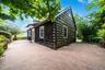 Exterior featuring dark wood-shake siding, expansive wrap around concrete patio, and decorative masonry perimeter wall