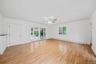 Spacious room featuring laminate flooring, a ceiling fan with integrated lighting, French doors that lead to covered patio and interior access to rear