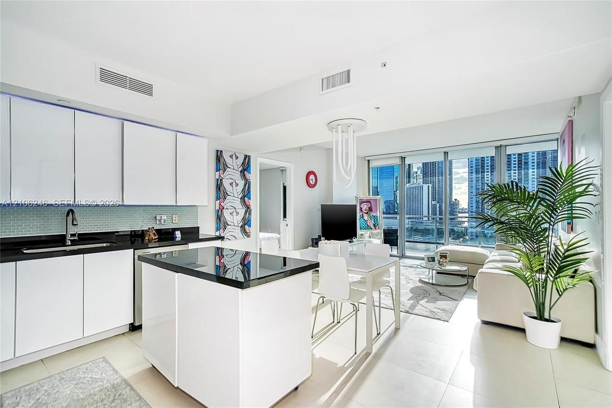 Kitchen featuring flat-panel white cabinetry, black stone countertops, tile backsplash, a matching center island, and floor-to-ceiling glass windows