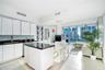 Kitchen featuring flat-panel white cabinetry, black stone countertops, tile backsplash, a matching center island, and floor-to-ceiling glass windows