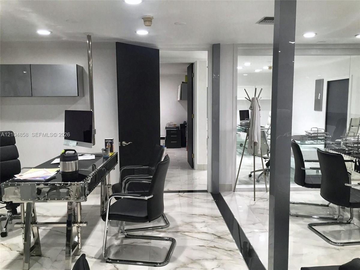 Polished stone flooring with decorative veining, recessed lighting, high-gloss wall-mounted cabinetry, and expansive glass partition wall